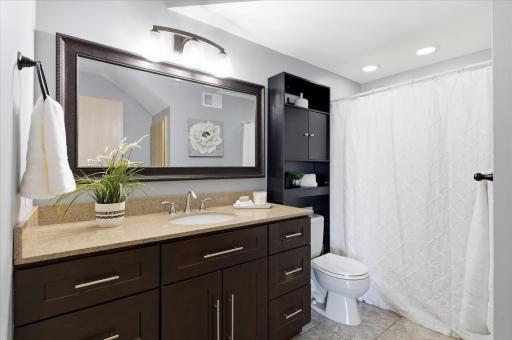 Updated full bathroom with granite vanity, modern fixtures, and tiled flooring.