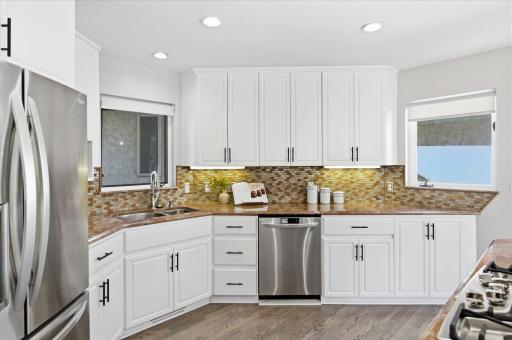 Wraparound kitchen layout with abundant cabinetry, prep space, and natural light from dual windows.