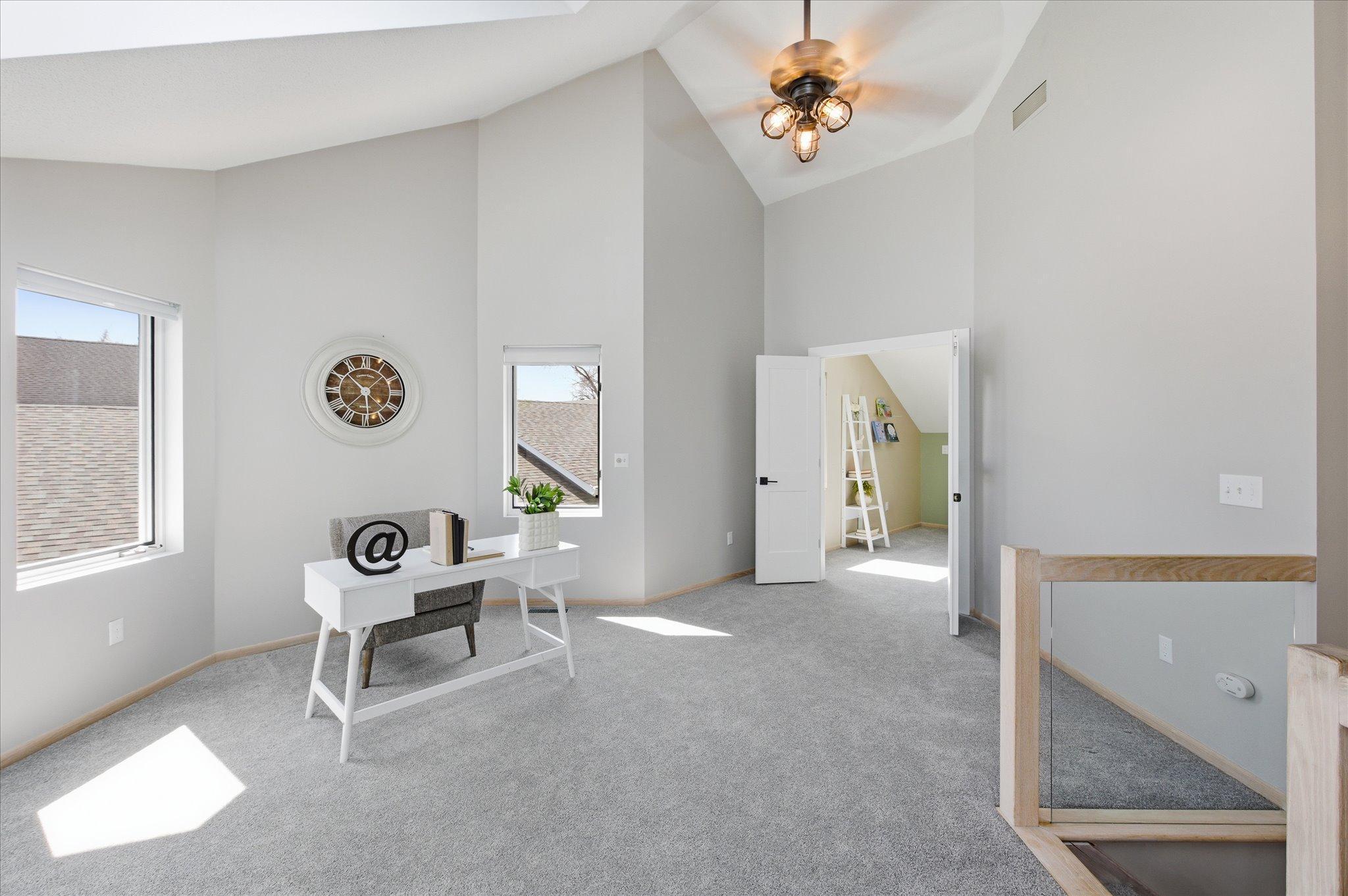 Spacious upper-level loft with vaulted ceilings, natural light, and flexible space for office or lounge.