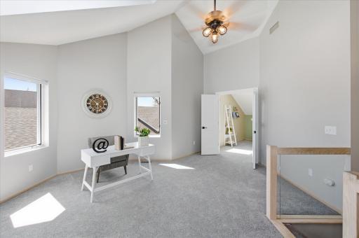 Spacious upper-level loft with vaulted ceilings, natural light, and flexible space for office or lounge.