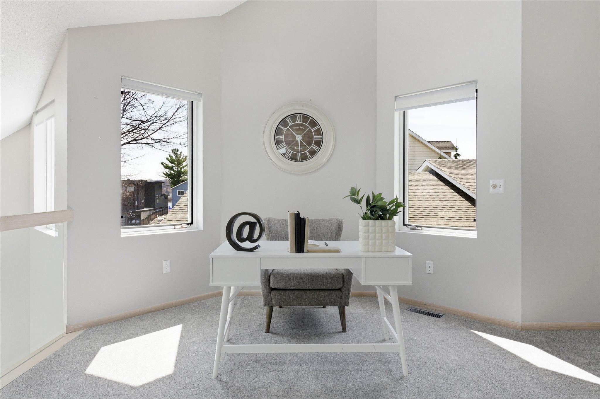 Bright loft workspace framed by windows—ideal for a home office or reading nook.