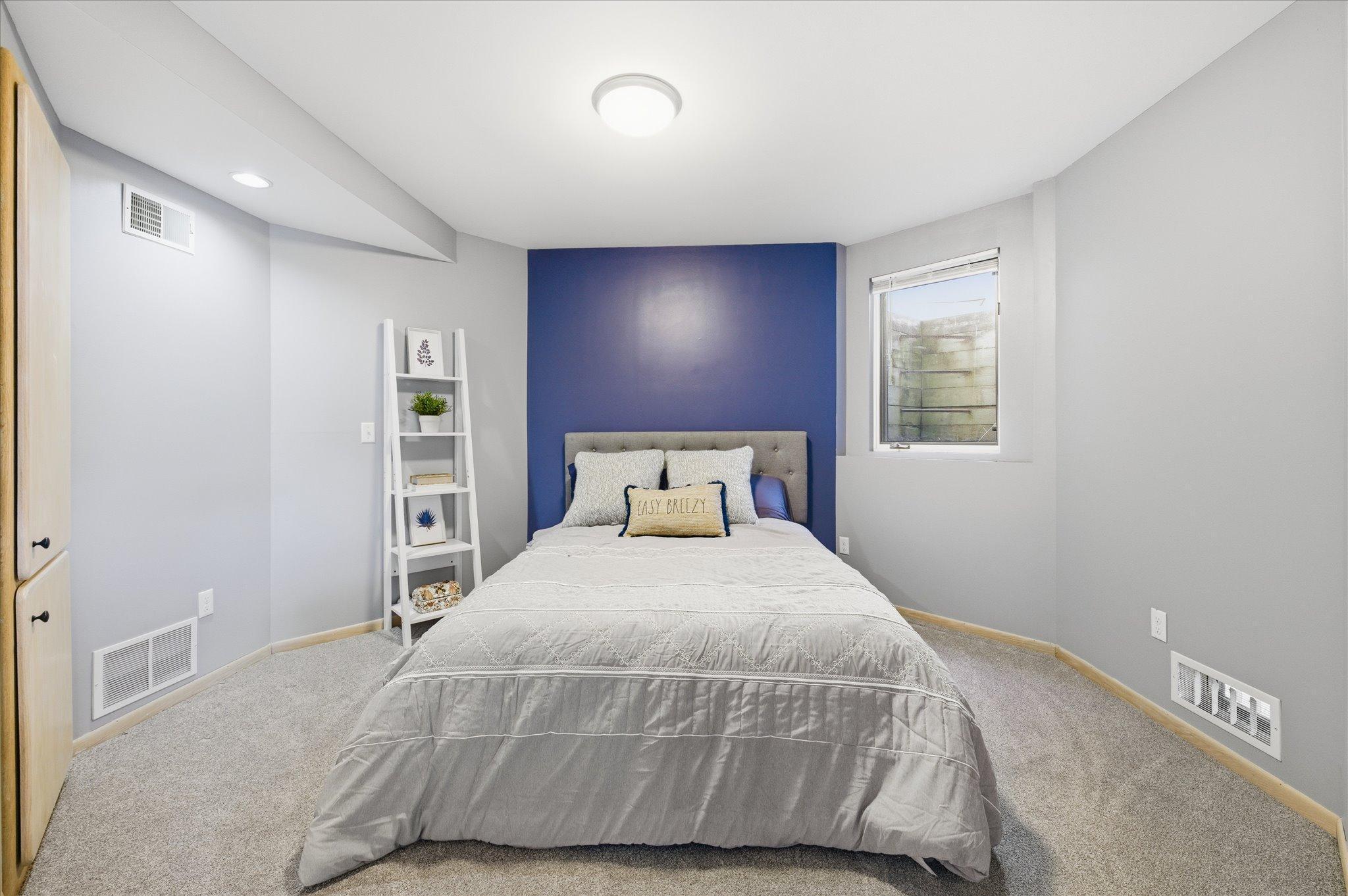 Lower-level bedroom with egress window, neutral tones, and comfortable layout.