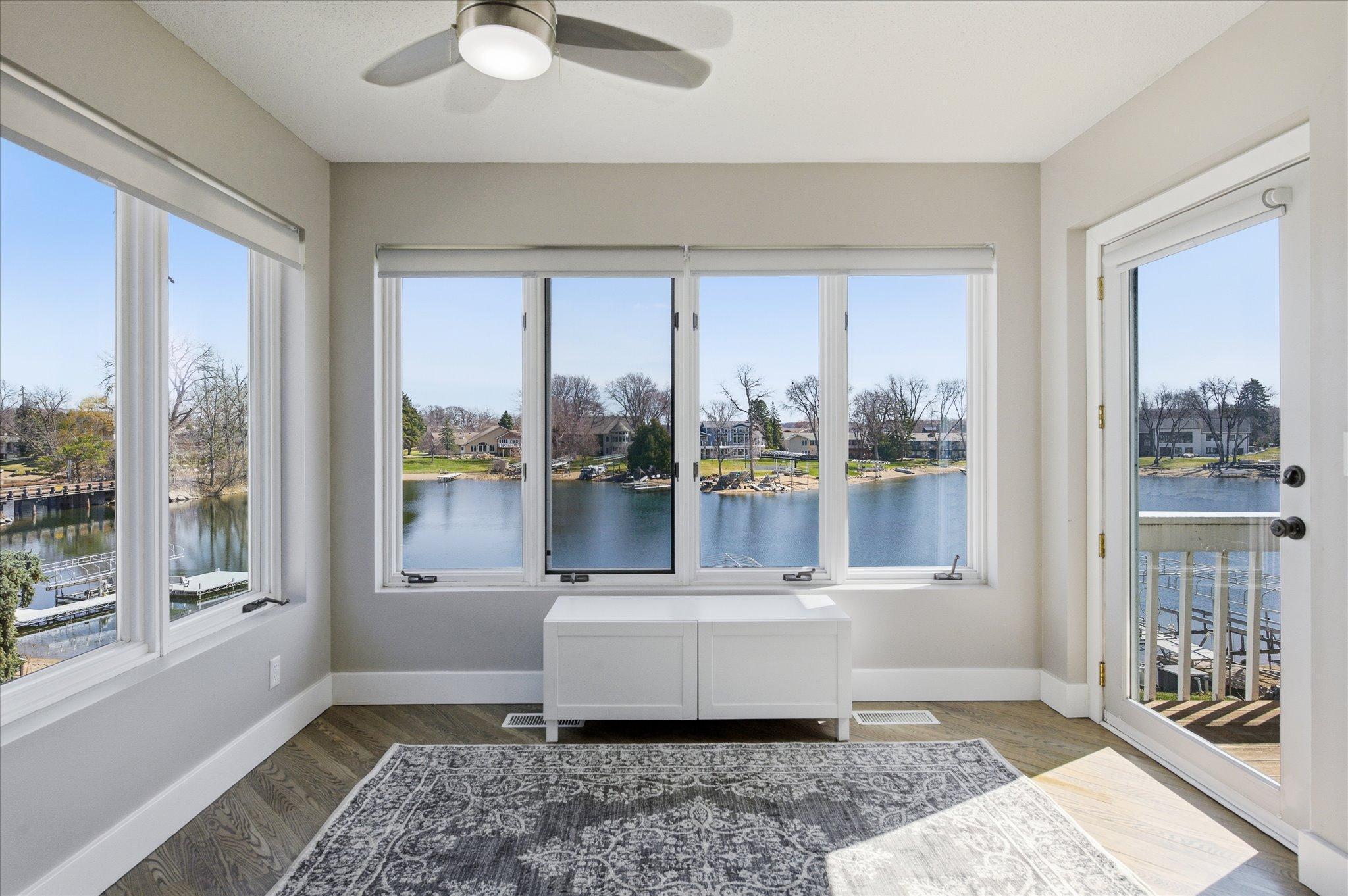 Light-filled flex space with panoramic lake views, surrounded by windows and offering direct access to the lakeside deck—perfect for a sitting room, office, or additional dining area.