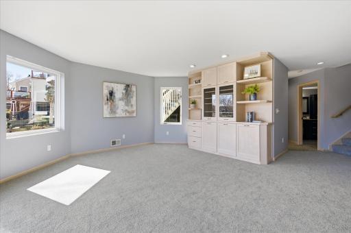 Spacious lower-level family room with plush carpet, recessed lighting, and custom built-in cabinetry for storage and display.