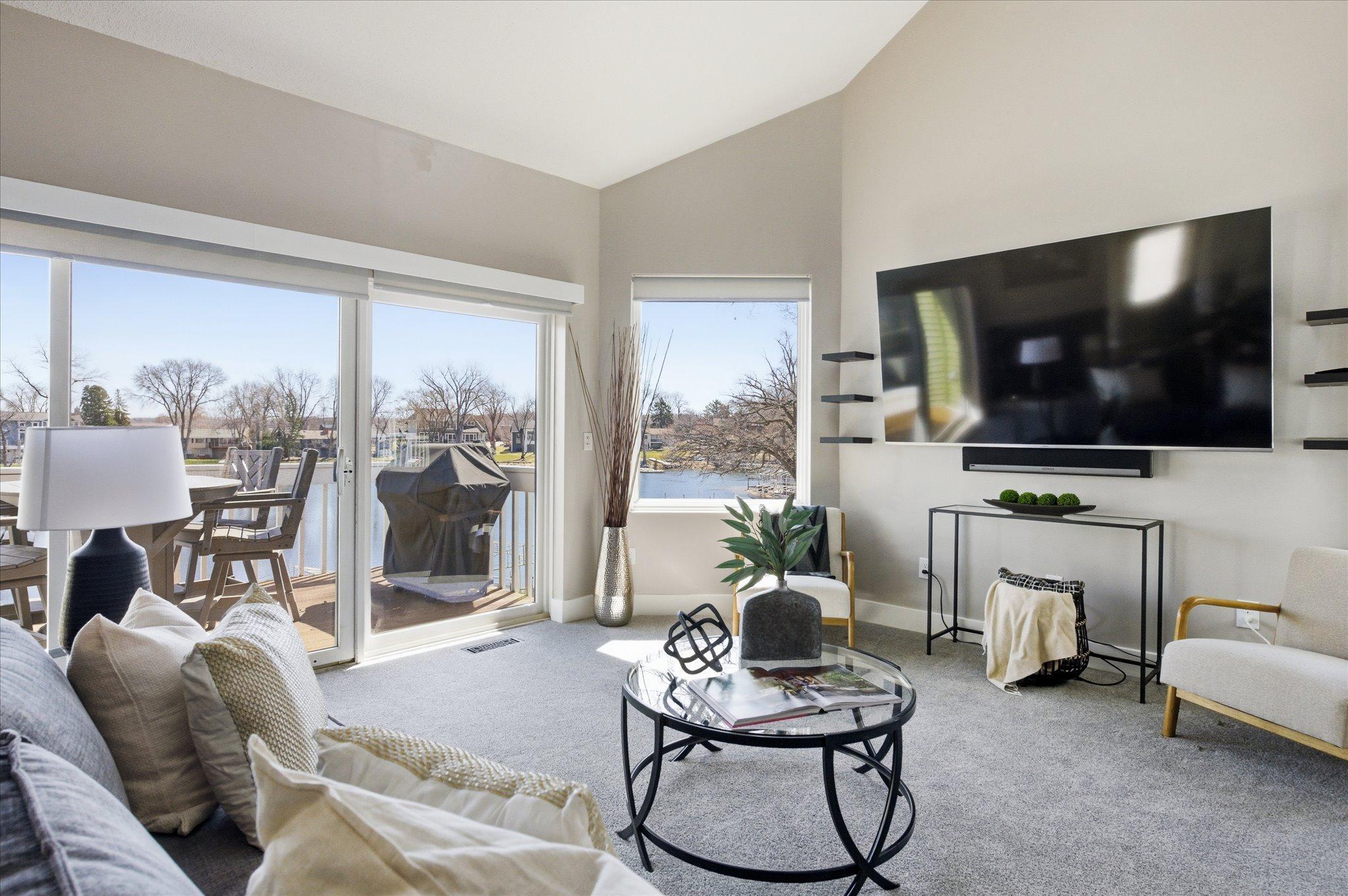 Another angle of the living room showcasing vaulted ceilings, natural light, and open layout.