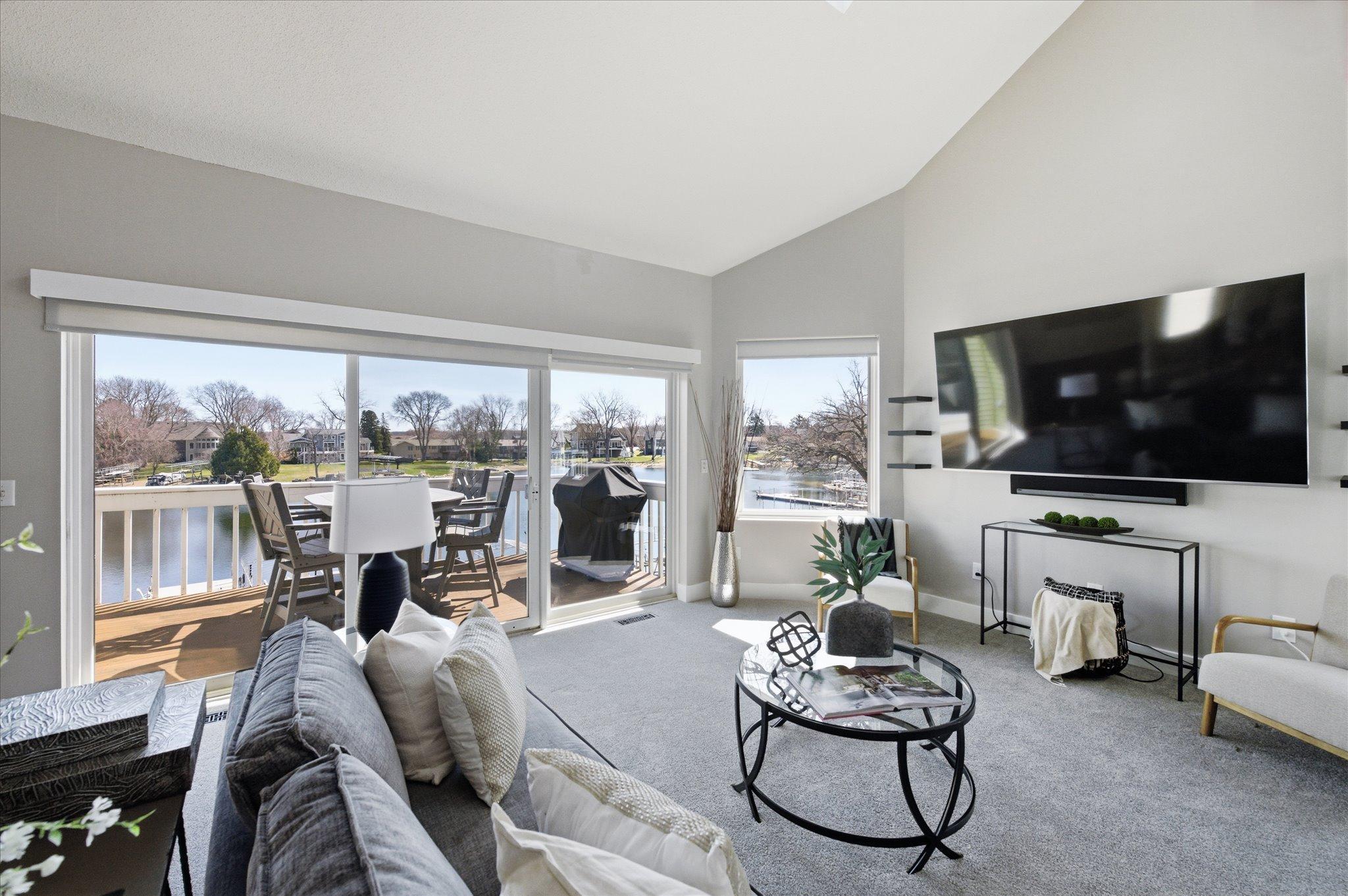 Light-filled living room featuring large picture windows and direct access to the lakeside deck.