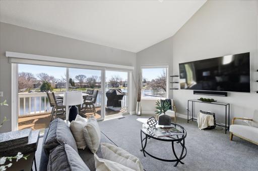 Light-filled living room featuring large picture windows and direct access to the lakeside deck.