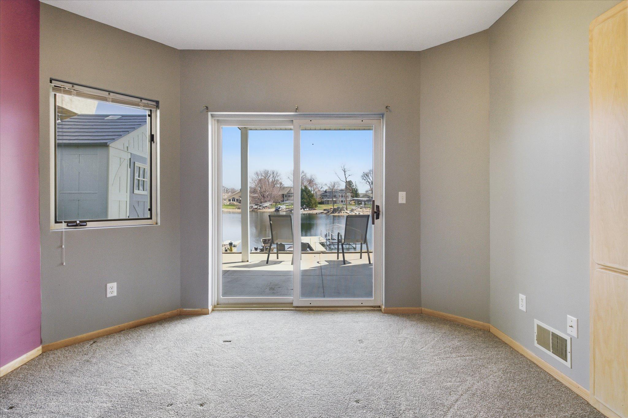 Secondary view of bedroom showcasing natural light and waterfront setting.