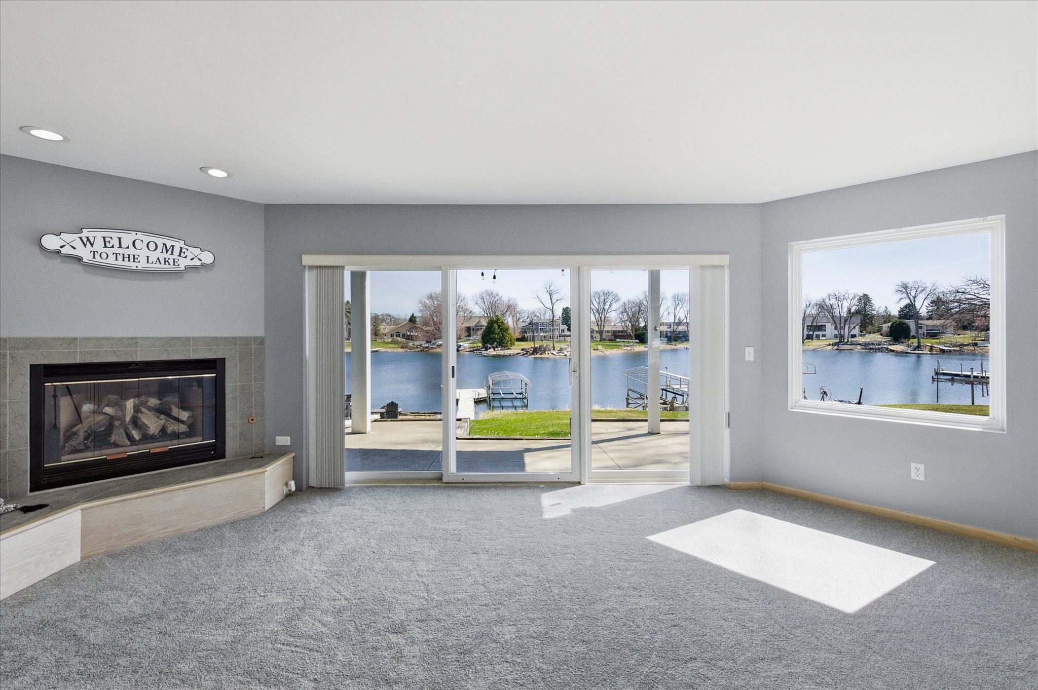 Light-filled walkout family room featuring a gas fireplace and expansive lake views through sliding glass doors.