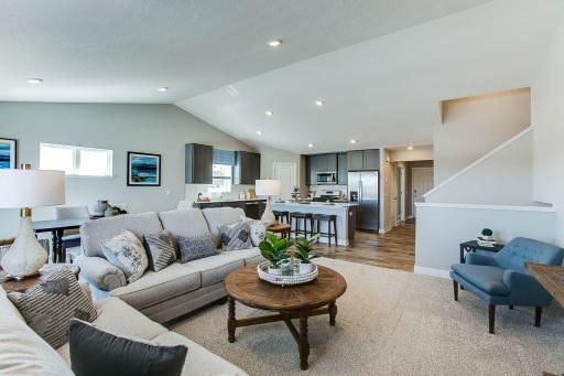 Main level living room and a glimpse of the entryway, guests arrive and flow right into the main floor. *Picture is of model home; actual finishes may vary.