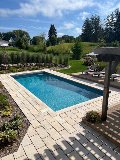 Outdoor amenities include a heated, inground swimming pool, maintenance-free sundeck with pergola, gas lined fire pit, gas line for grill, professional landscaping with irrigation, and extended the three-season porch.
