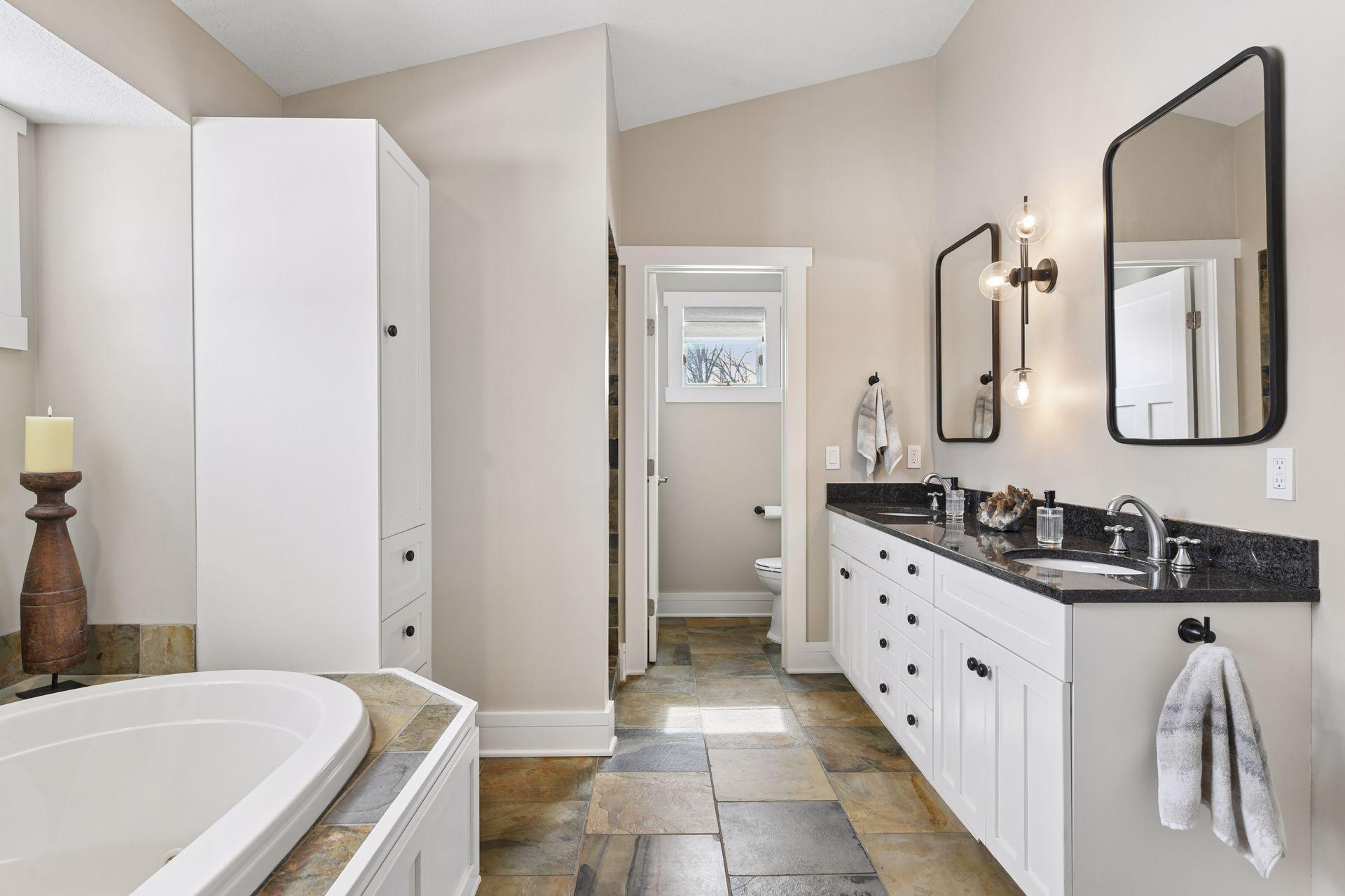 Private primary en-suite with tile floors, double sink vanity, jacuzzi tub, and a walk-in shower