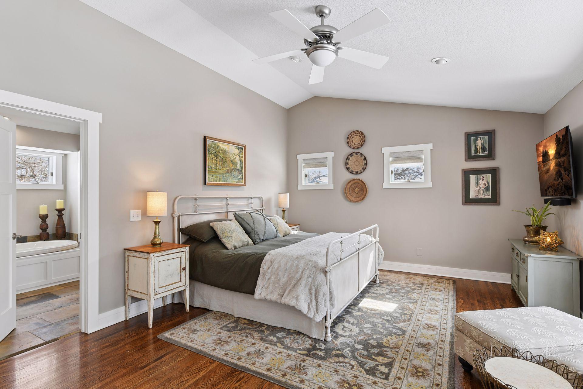 Upper level primary bedroom with newer wood floors, vaulted ceilings, and a private en-suite