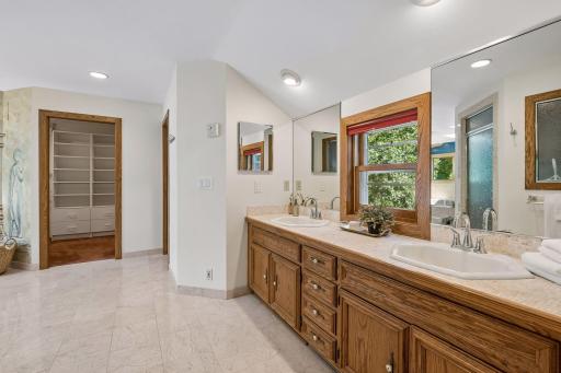 Expansive ownerâs ensuite featuring a double-sink vanity, tile flooring, spacious walk-in closet, and a luxurious six-person hot tub.