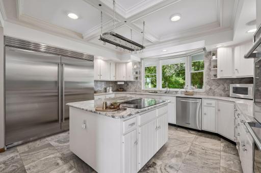 Custom kitchen featuring a Sub-Zero refrigerator/freezer (2025), tile backsplash, Cafe double ovens, granite countertops, and a beautiful coffered ceiling.
