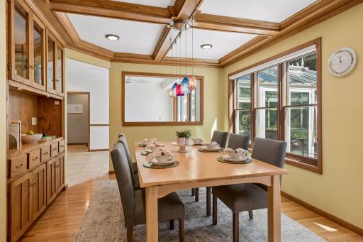 Natural light fills the formal dining room, featuring custom built-ins and a beautiful coffered ceiling.