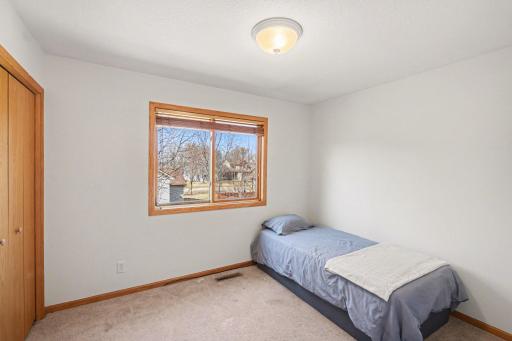 The 2nd bedroom on the upper level has an updated light fixture, and a west-facing window with wood blinds & seasonal lake views.
