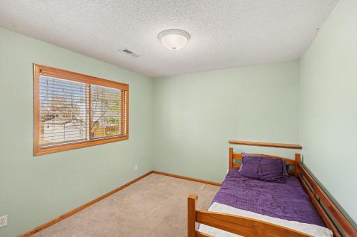 The 5th bedroom in the lower level features: a west-facing window with wood blinds, and an updated light fixture.