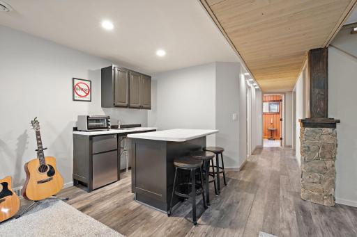 The lower level wet bar has a mini refrigerator. The lower level bathroom and bedroom are down the hallway.