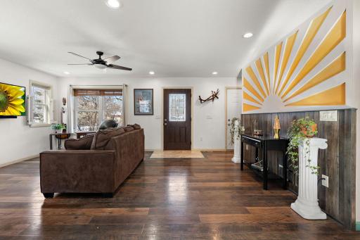 The living room features windows facing the street. The front door is across the room with garage door access on the right.