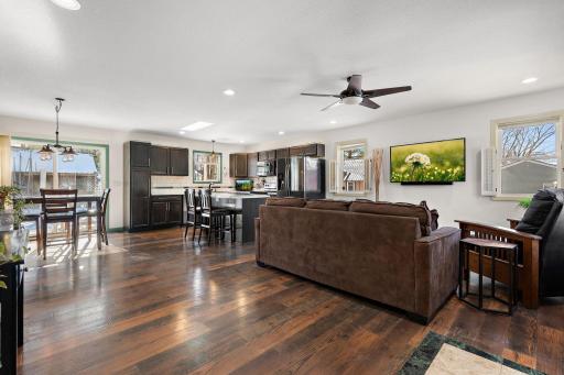 Standing near the garage access door and looking into the dining area on the left, the kitchen and the living room across the way. The space flows seamlessly with many windows spaced between to allow plenty of light.