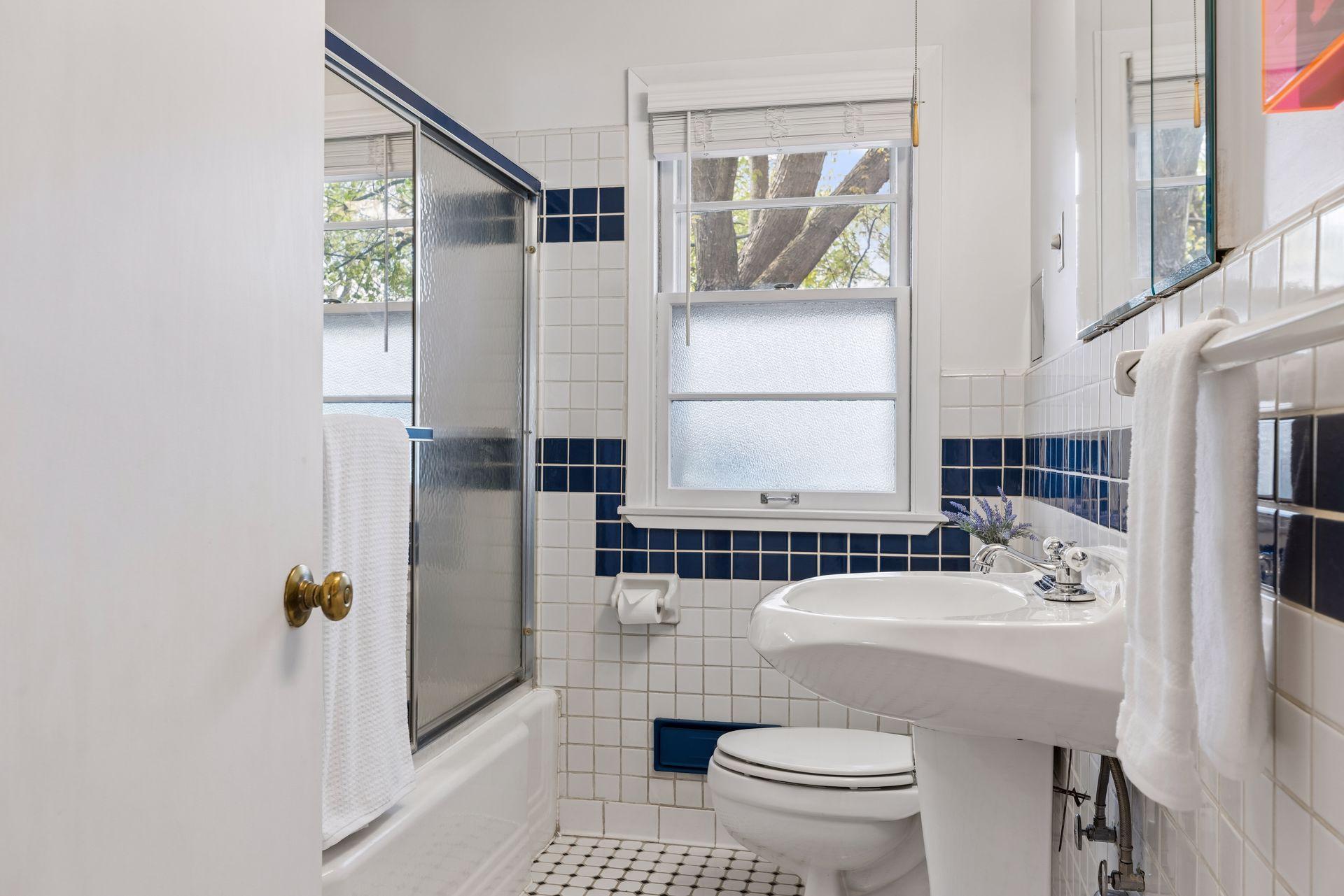 The blue-and-white tiled bath brings a bright pop of 1950s personality