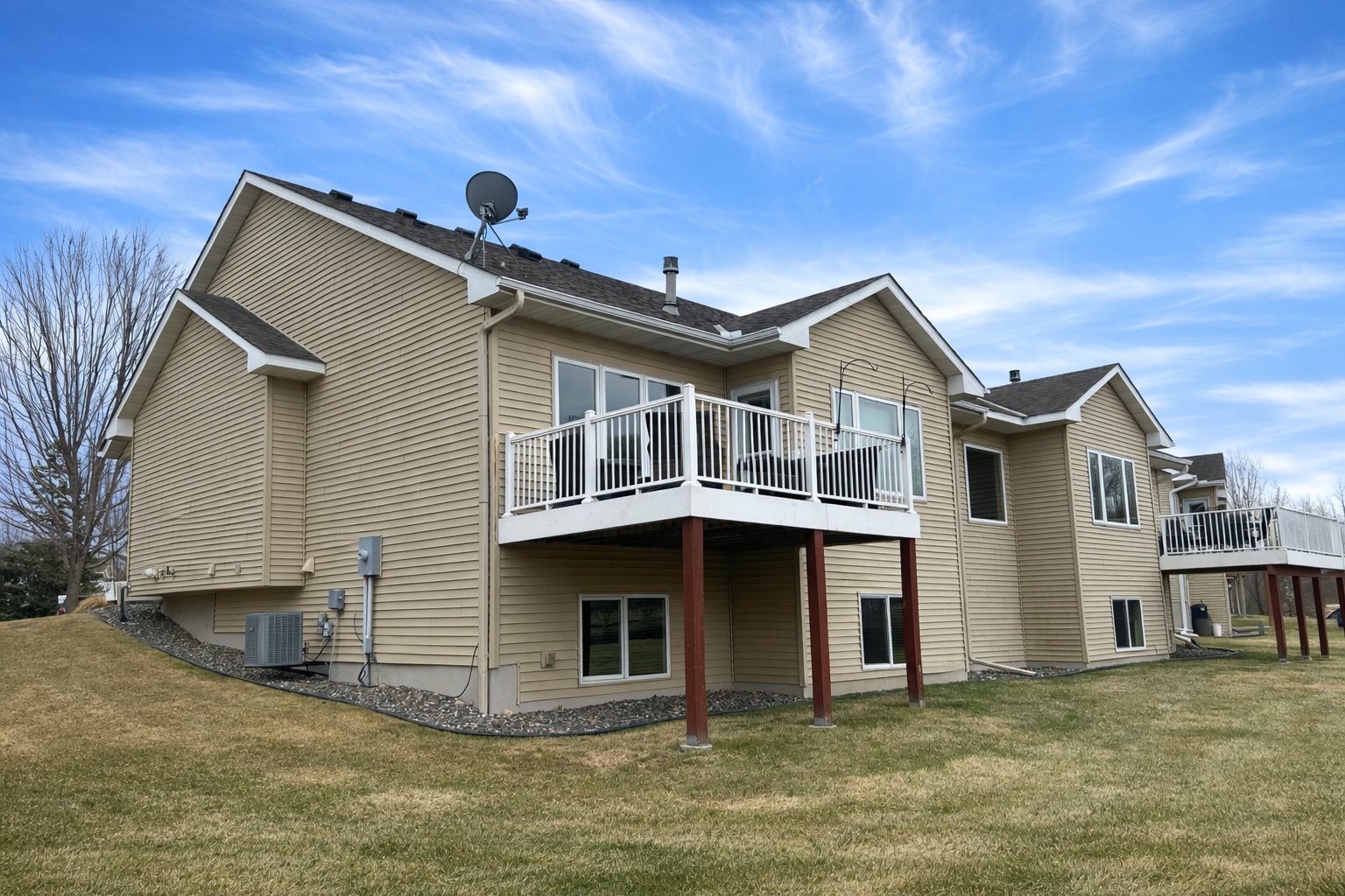 Back of home - spring. The deck has composite flooring and a newer metal railing.