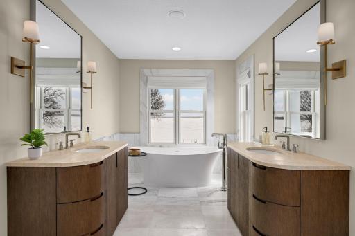 This luxurious bathroom has been fully updated with high-end finishes and a spa-like layout. The soaking tub is positioned to overlook the lake.