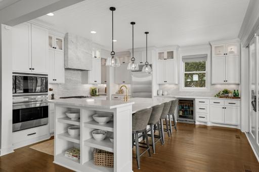 This modern kitchen features a spacious center island with a stylish accent niche, new countertops and striking vent hood and backsplash, timeless lighting and hardware.