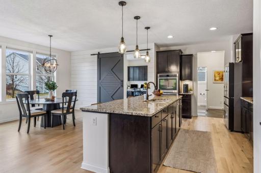 Spacious kitchen with large center island and adjacent dining, plus a sliding barn door opening to a command center that keeps daily life organized.