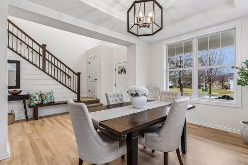 Open view to the front entry and staircase, where iron railing, warm woodwork, and shiplap create a refined contrast.