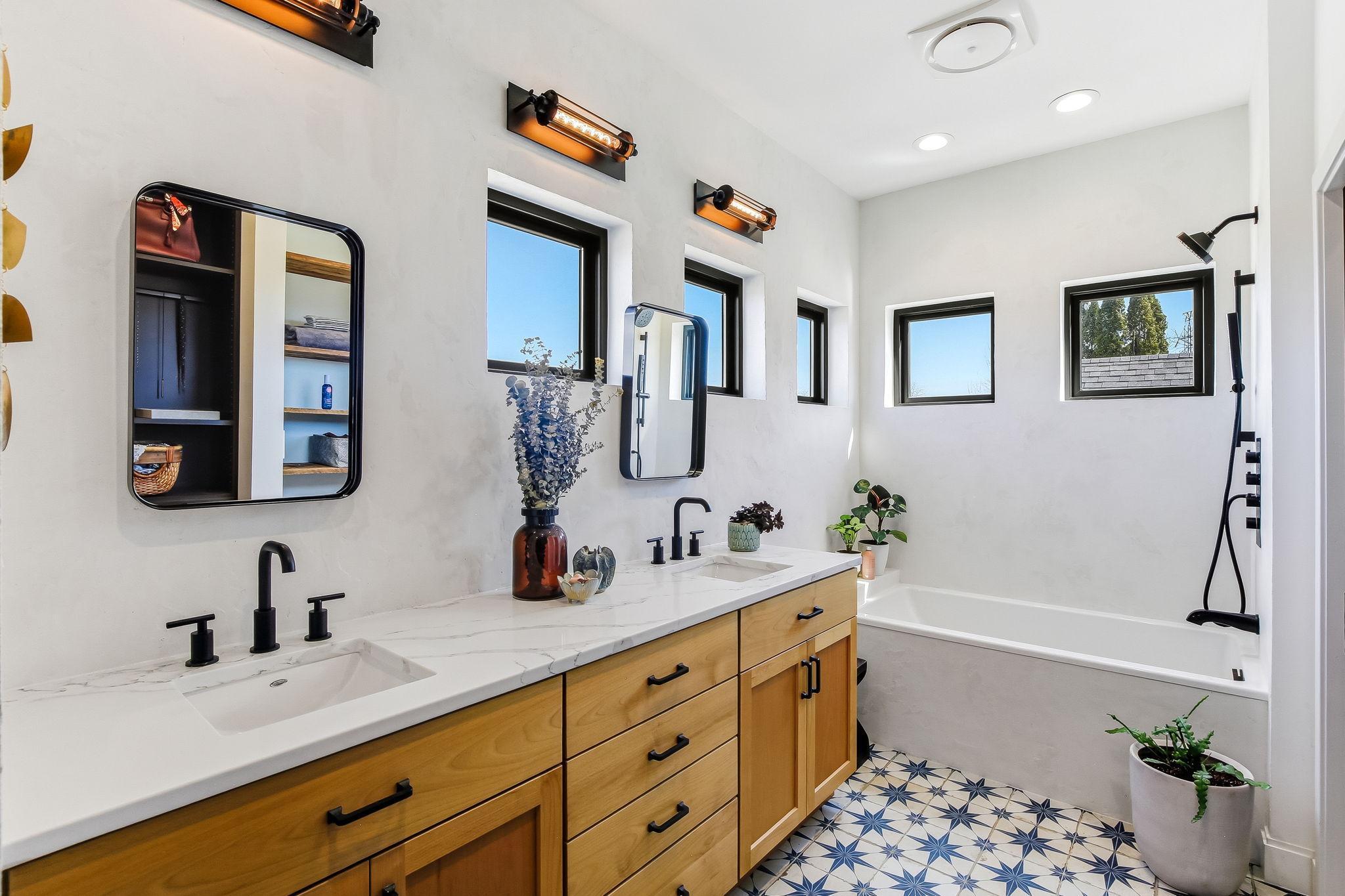 Modern primary en suite featuring dual sinks, a deep luxurious bathtub, heated floors and contemporary finishes for style and functionality