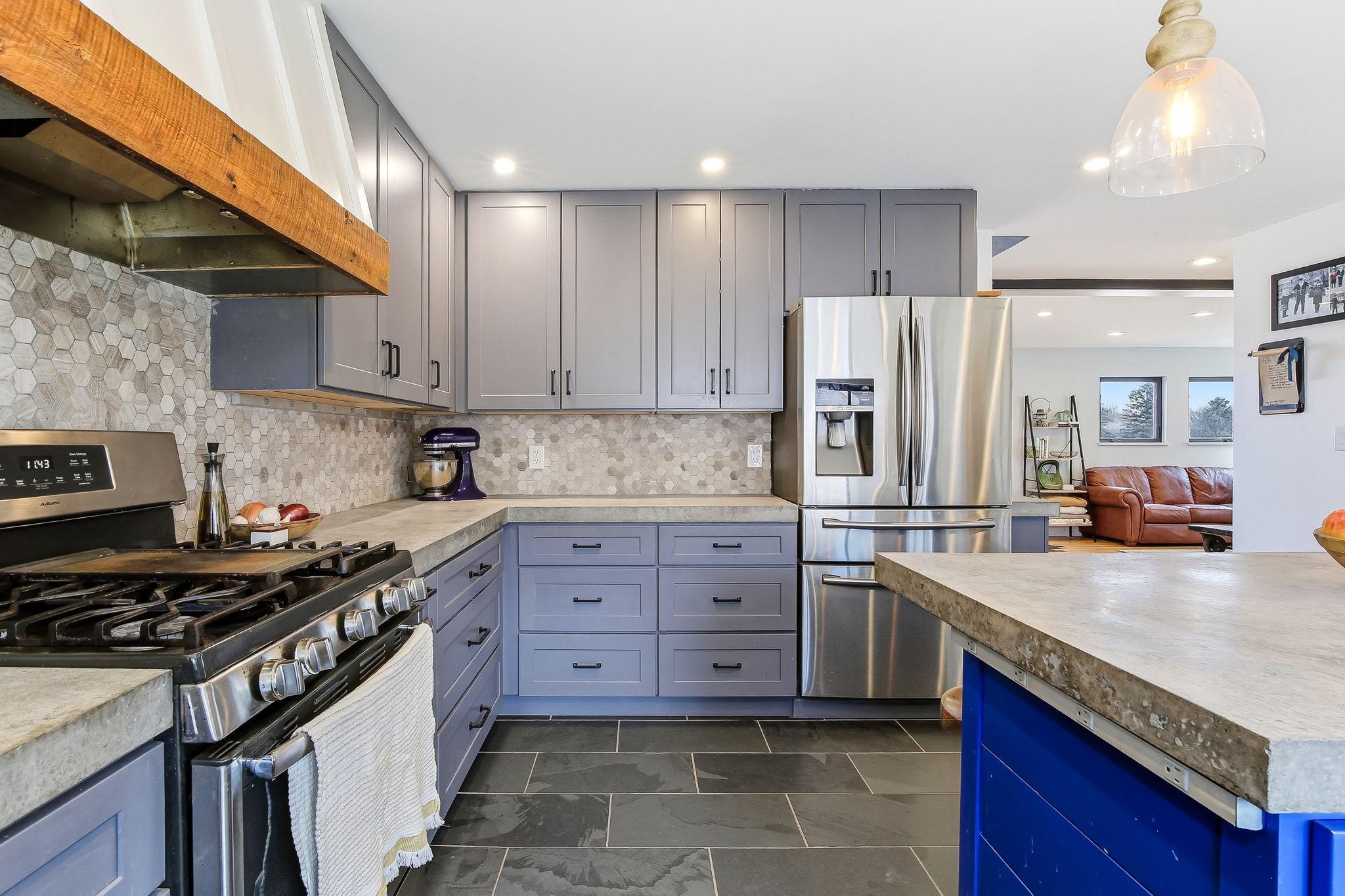 Modern elegance in the kitchen with tall custom cabinets, stone backsplash, and heated slate tile floor.