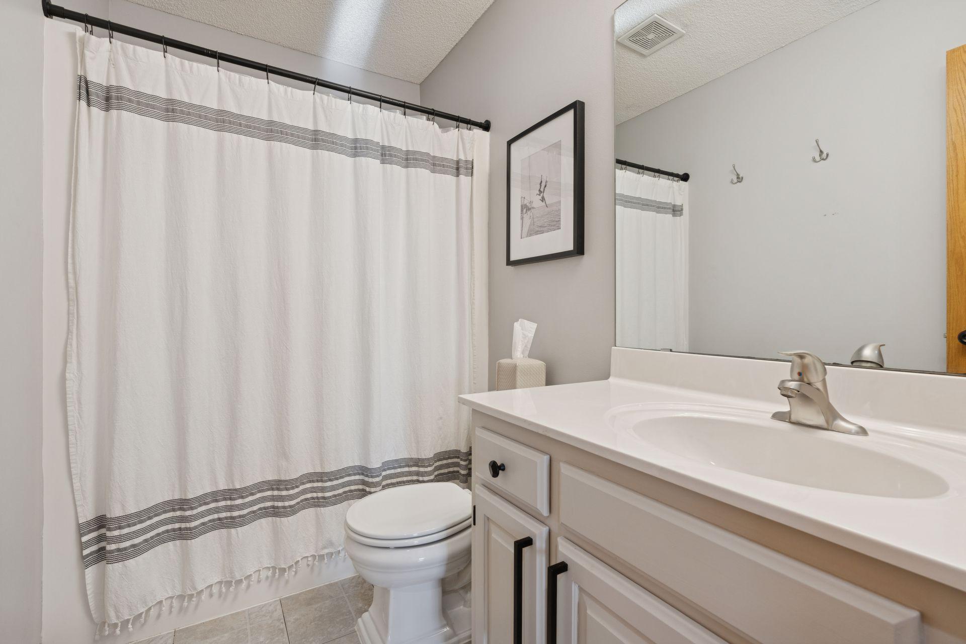 Upper level full bath w/ refinished cabinetry.