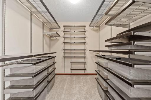 This exceptional walk-in closet, featuring a custom-designed storage system with extensive shelving, built-in drawers, and hanging space for every wardrobe need.