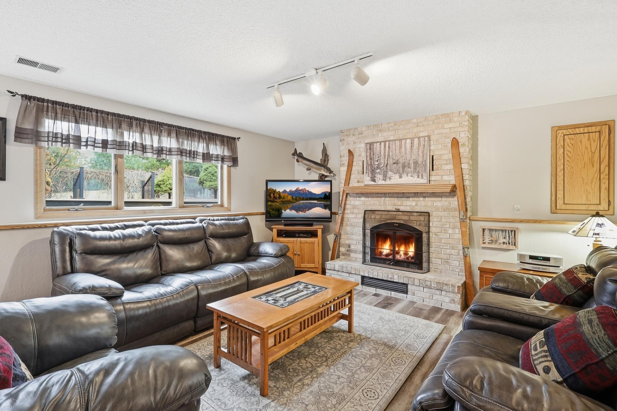 The lower-level impresses with exceptional entertaining space featuring a striking wood burning fireplace, a remodeled bath with a beautifully tiled walk-in shower, and ample storage space.