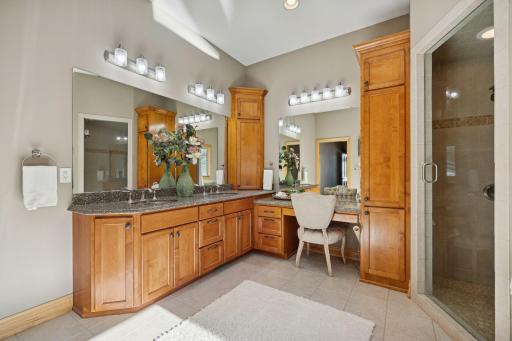 Spacious primary bath with dual vanities, granite counters, and a dedicated makeup area for everyday luxury.