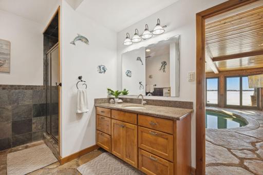 Poolside bathroom with warm wood cabinetry, a spacious vanity, and direct access to the indoor pool area