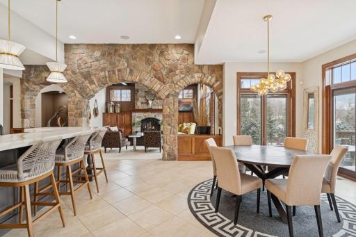 A stunning floor-to-ceiling stone feature wall with arched openings creates a warm, architectural focal point, beautifully connecting the kitchen and living room.