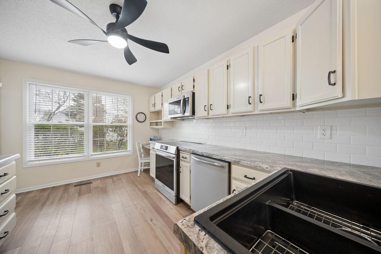 Abundance of freshly enameled cabinets with new hardware, counterops, subway-style backsplash, sink, and faucet.