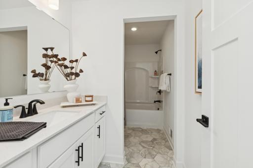 (Photo of actual model) This shared full bathroom features dual sinks and a shower-tub combination.
