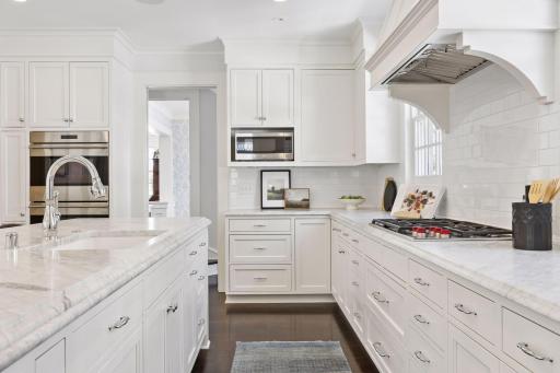 Chef's kitchen with Wolf 5 gas burner cooktop, two Wolf wall ovens, foot heater below kitchen sink and ample counter space