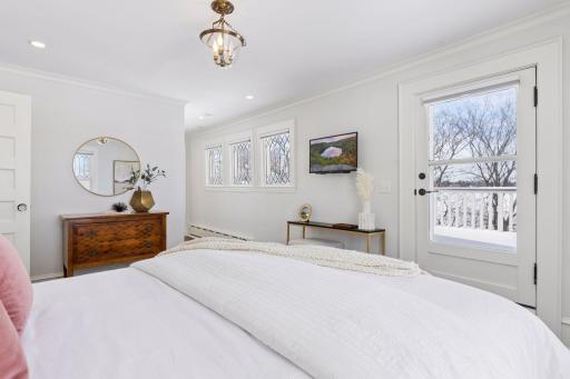 Primary bedroom with leaded glass windows and access to large private deck with stunning lake views