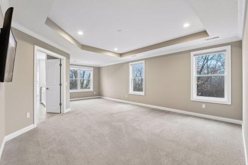 Upstairs, the Primary Bedroom is a tranquil retreat with a tray vault ceiling and sitting area that overlooks the backyard.