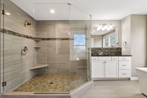 The spacious shower features a frameless glass enclosure.
