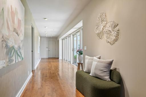 The gallery hallway features hardwood floors, a wall of glass overlooking the courtyard and access to the powder room, secondary bedroom ensuite and laundry/mud room.