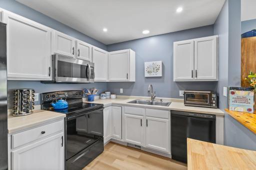 The kitchen features newer appliances including a stainless steel microwave, and sleek black range, dishwasher and refrigerator.