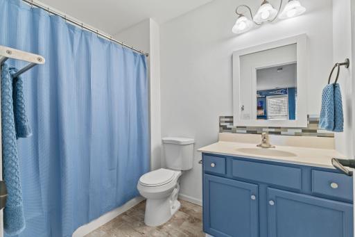 The lower level full bathroom features painted cabinetry, an updated light fixture, and backsplash.