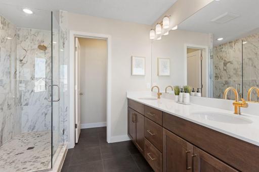 Owner's bathroom with tiled shower, double vanity, and separate stool area