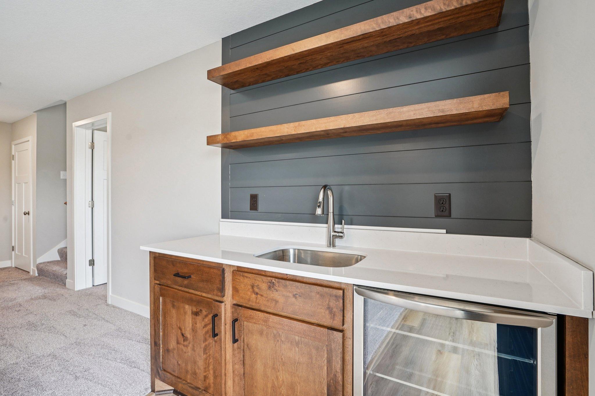 Lower level wet bar with fridge and feature wall.